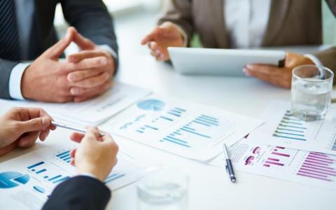 Business meeting with charts and documents on a table.